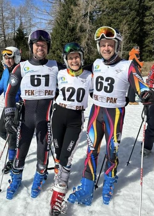 tre sciatori con le pettorine numerate posano per una foto di gruppo